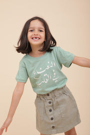 Petite fille avec un tshirt LYOUM en calligraphie ' La Menthe dans le cœur ' en arabe.