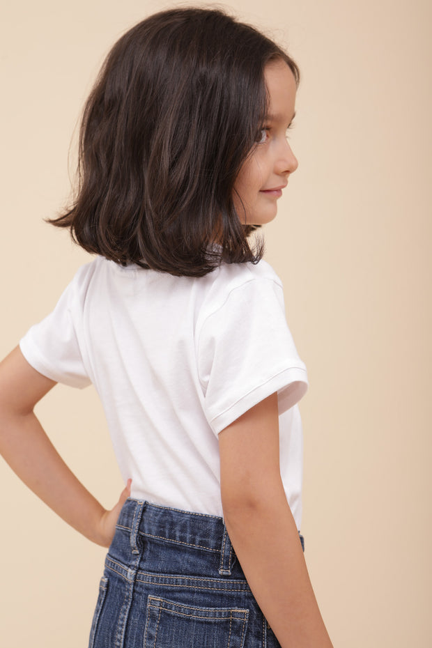 Petit fille de dos avec un tshirt blanc et une petite jupe en denim.