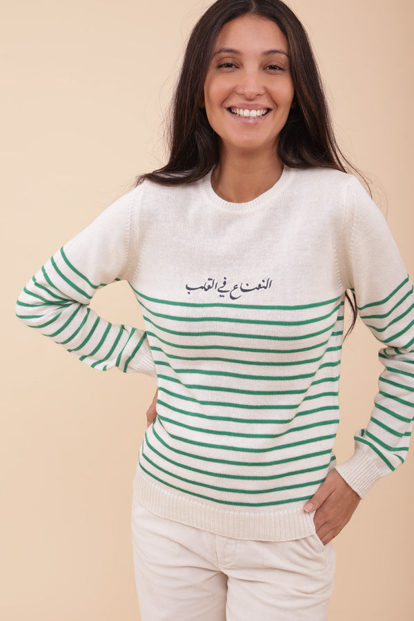 Femme en pull en maille LYOUM, calligraphie brodée.