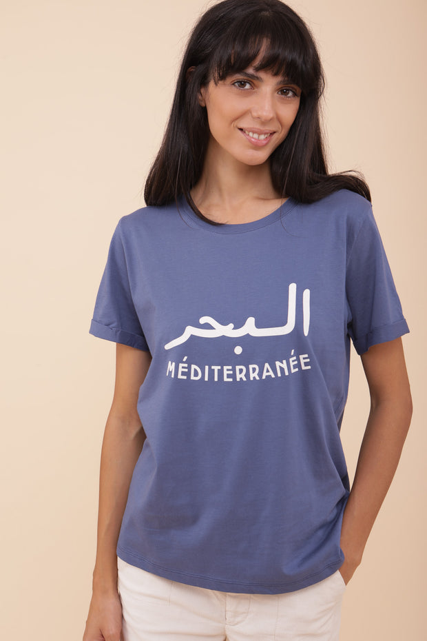Femme portant le tshirt bleu sombre 'La Mer Méditerranée' en mix arabe/français.