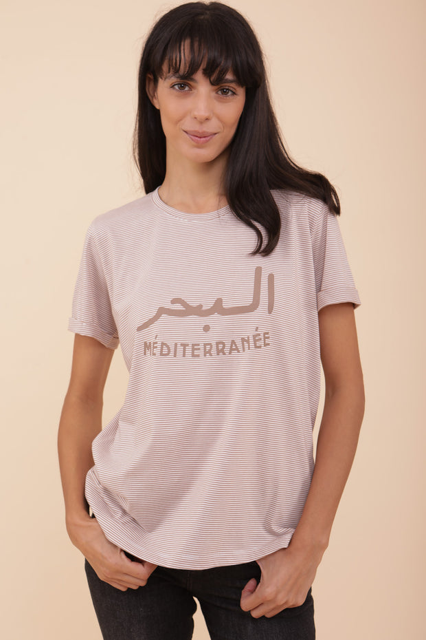 Femme portant le tshirt 'La Mer Méditerranée' en mix arabe/français , maintenant à rayures sable !
