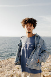 Homme en tshirt LYOUM à calligraphie, face à la Méditerranée.