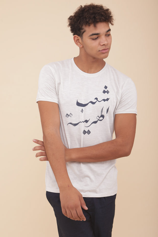 Il porte notre t-shirt avec une coupe droite impeccable : 'Harissa People' en Arabe.
