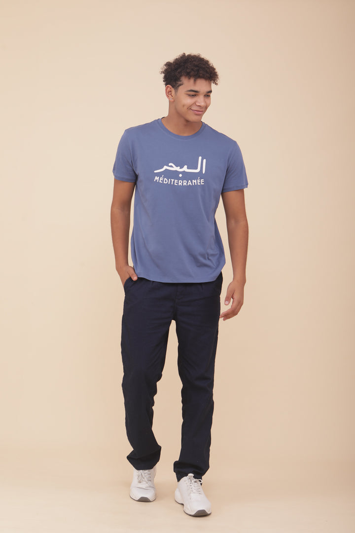 Il porte le t-shirt qui a une coupe droite : ' La Mer Méditerranée ' en mix arabe/français.