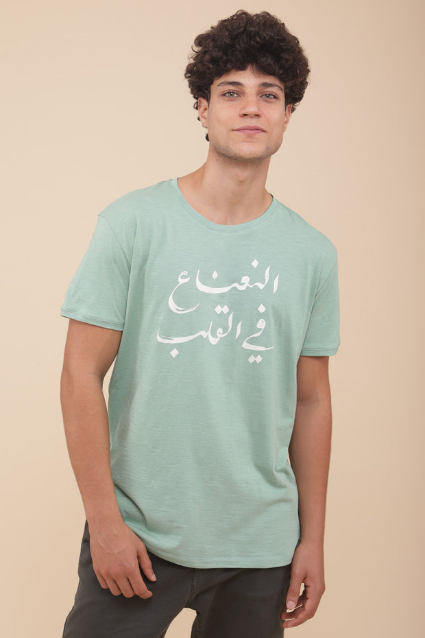 Il porte le t-shirt 'La menthe dans le cœur' en arabe avec une coupe droite impeccable.