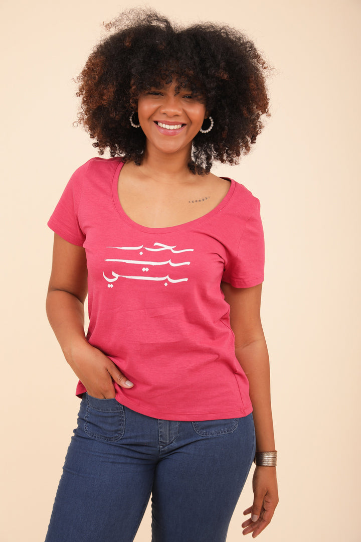 Femme souriante en tshirt LYOUM rose, la main dans la poche.