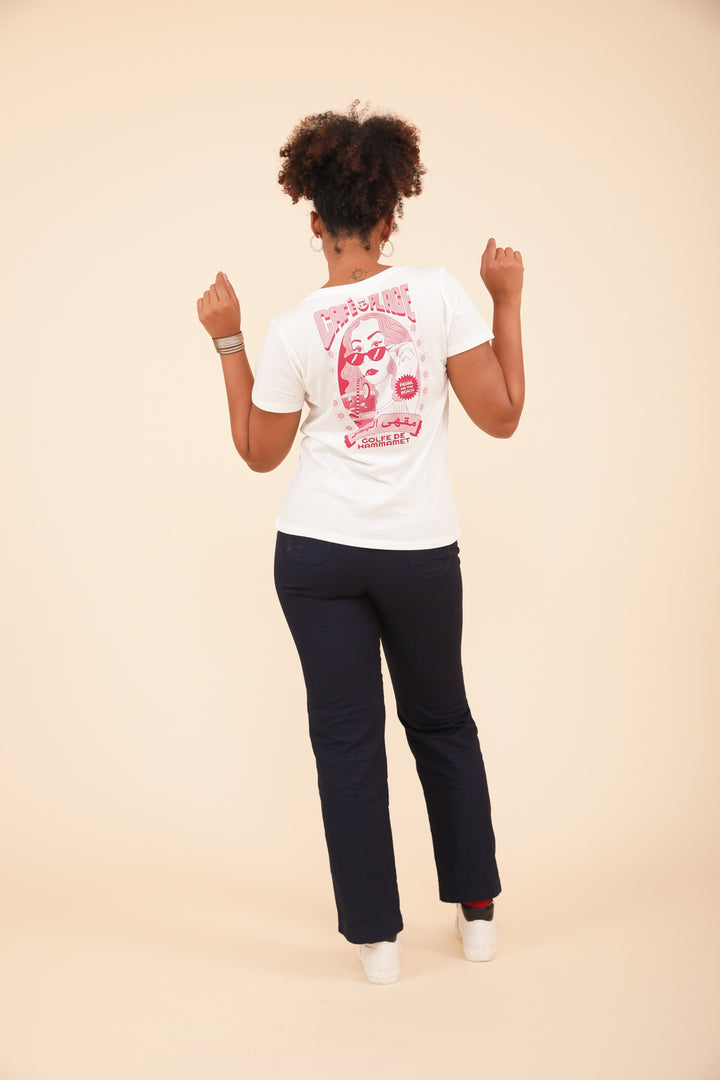 Femme en tshirt LYOUM blanc avec illustration rose, et pantalon bleu.