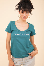 Femme brune en t-shirt décolleté LYOUM vert émeraude.