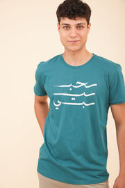 Homme qui porte un tshirt LYOUM vert Habibi en arabe.