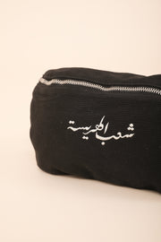 Zoom sur le sac banane LYOUM noir et sa calligraphie arabe.