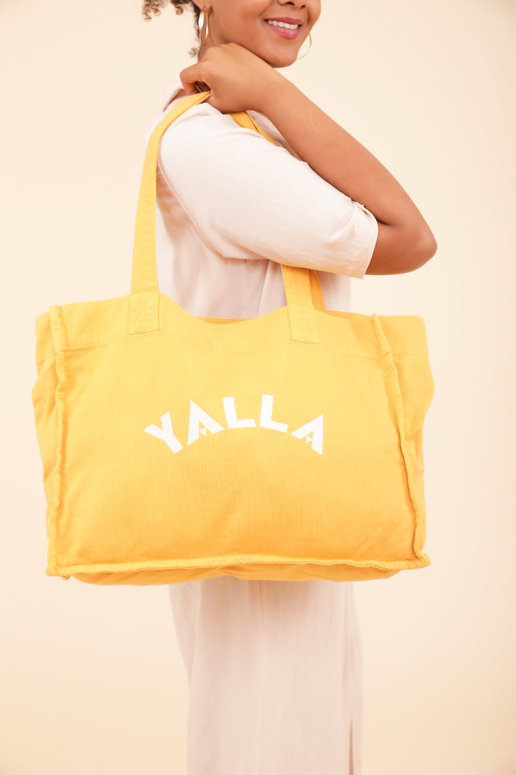 Femme portant à l'épaule le sac LYOUM jaune.