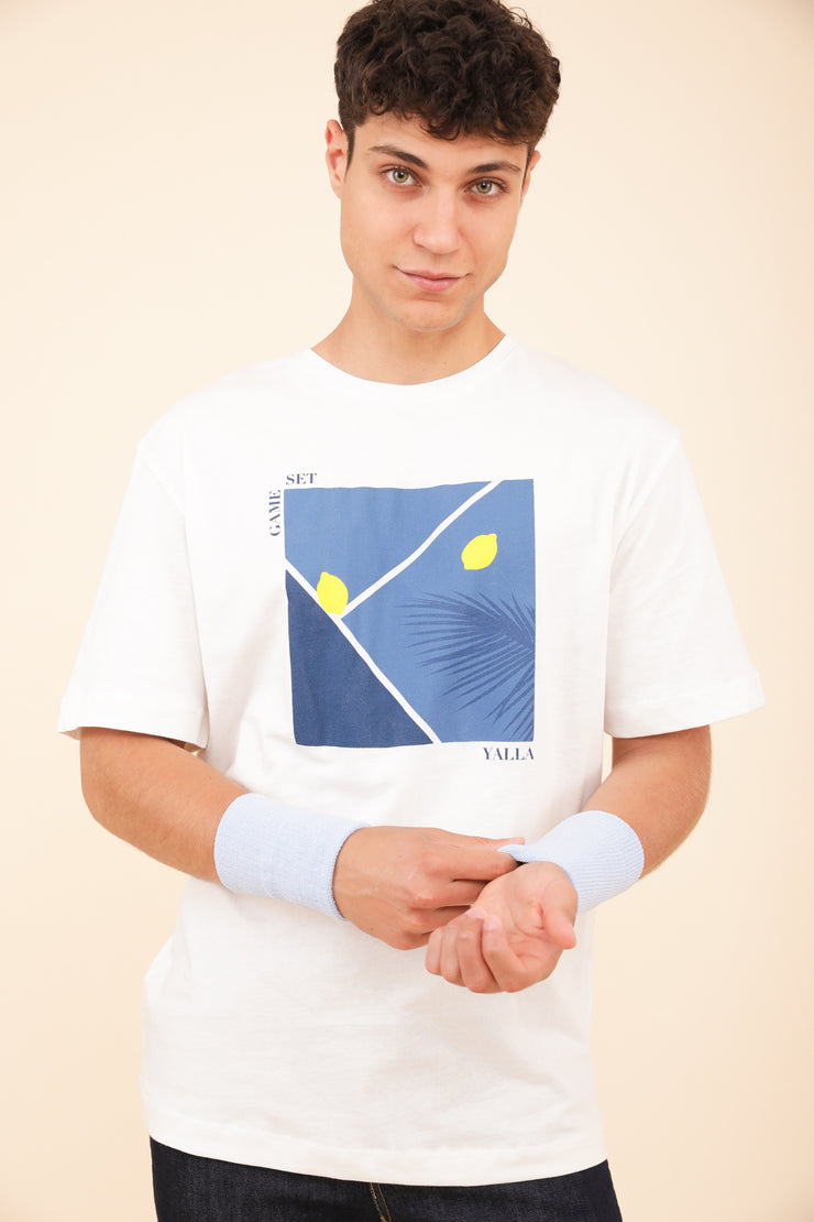 Homme en t-shirt LYOUM sport blanc et court de tennis bleu.