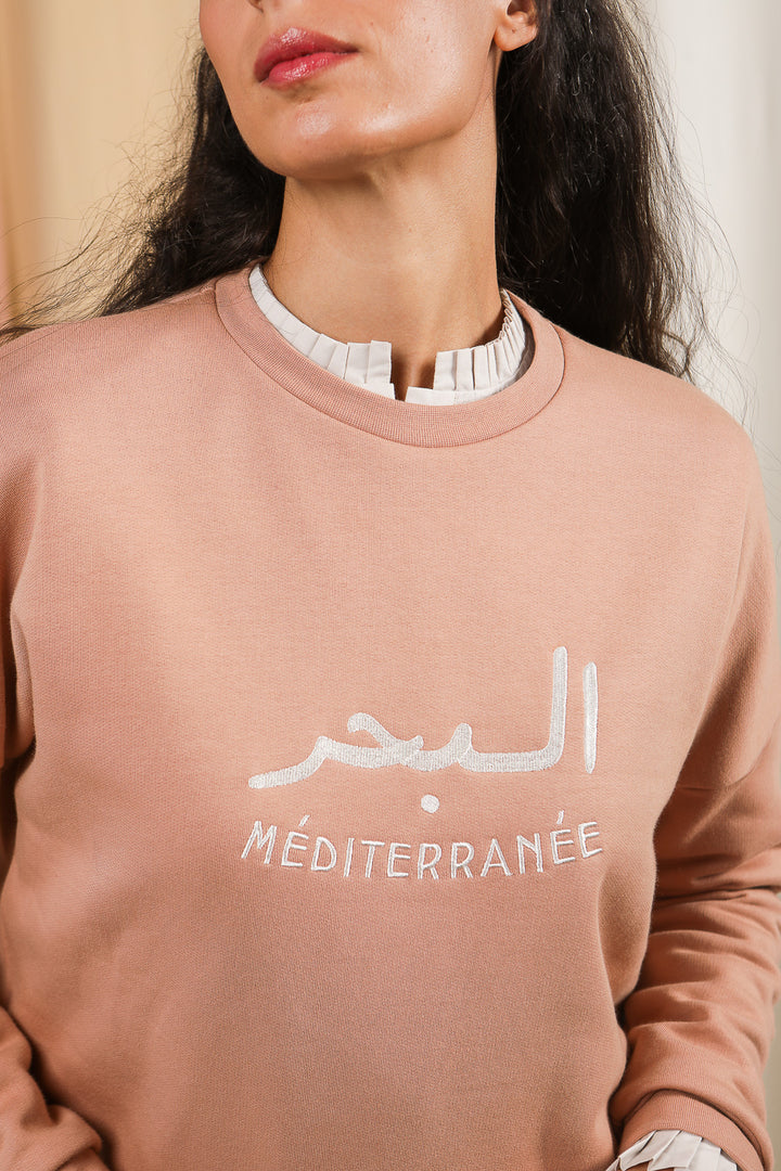 Détail de la broderie 'La Mer Méditerranée' en mix arabe-français sur le sweat en écru.