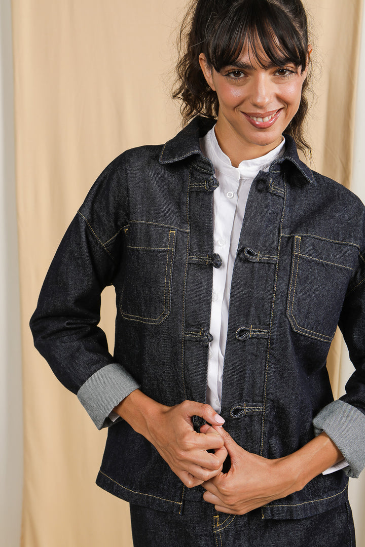 Femme brune en veste LYOUM Denim sur chemise blanche.