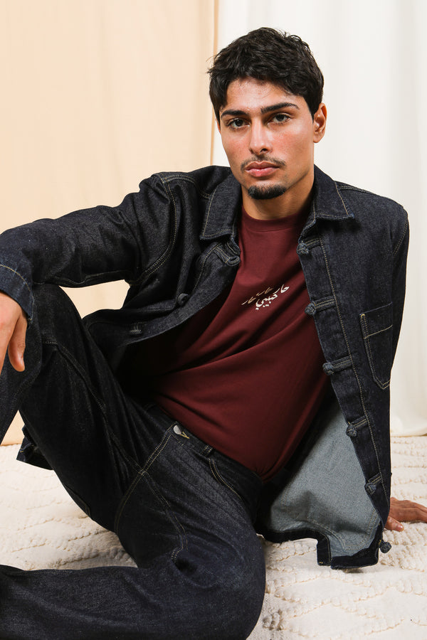 Homme assis en tenue LYOUM denim et tshirt bordeaux.