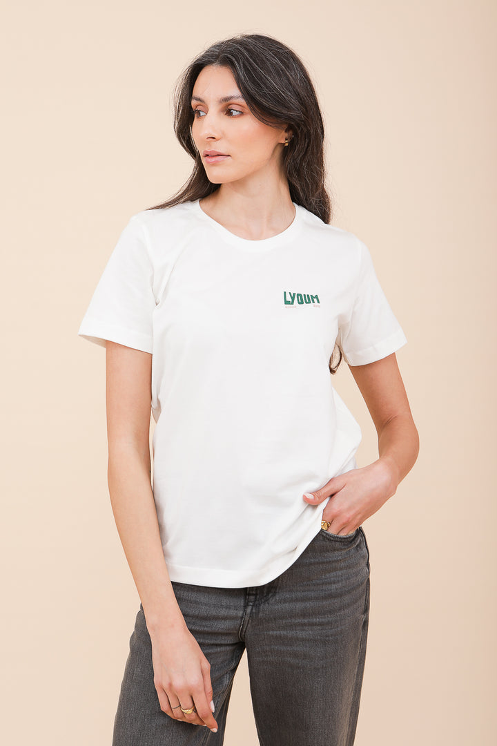 Femme brune en tshirt LYOUM blanc et jeans gris.