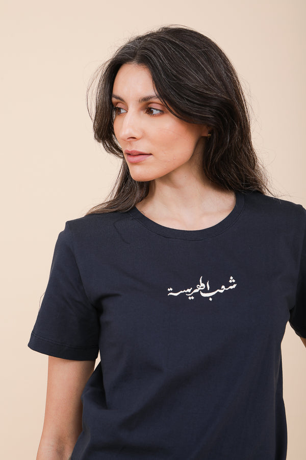 Femme aux cheveux longs noir en tshirt LYOUM bleu et calligraphie arabe écru.