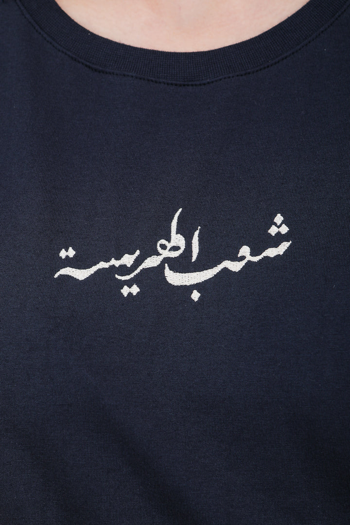 Calligraphie arabe LYOUM Peuple de la Harissa brodée sur tshirt bleu.