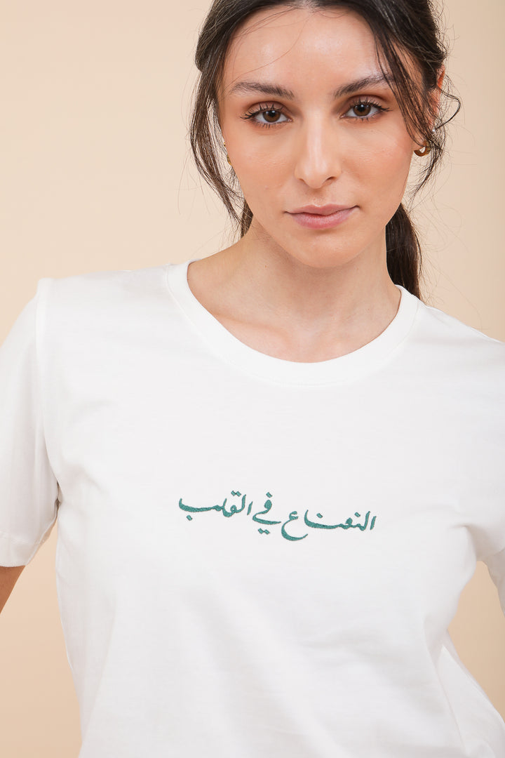 Femme en queue de cheval et tshirt LYOUM blanc avec sérigraphie arabe.