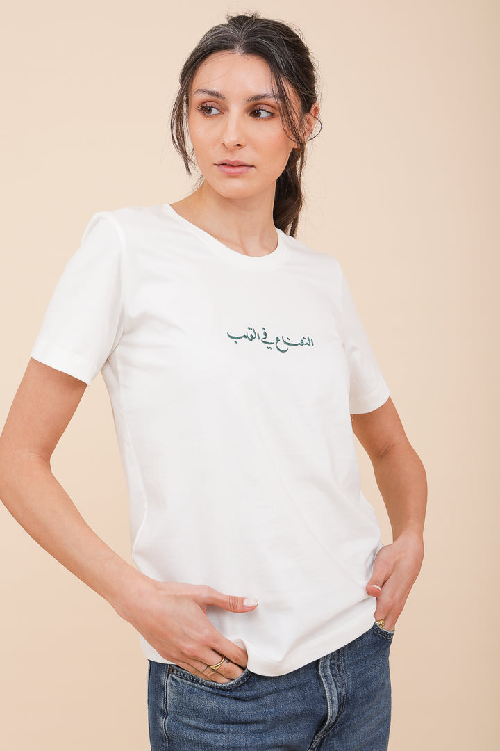 Femme en tshirt blanc avec écriture sur le devant, les mains dans les poches.