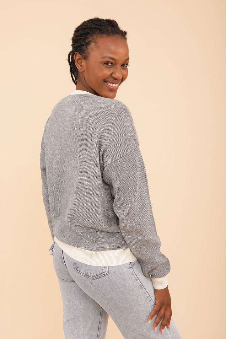 Femme qui sourit dans son pull LYOUM gris vue de dos.