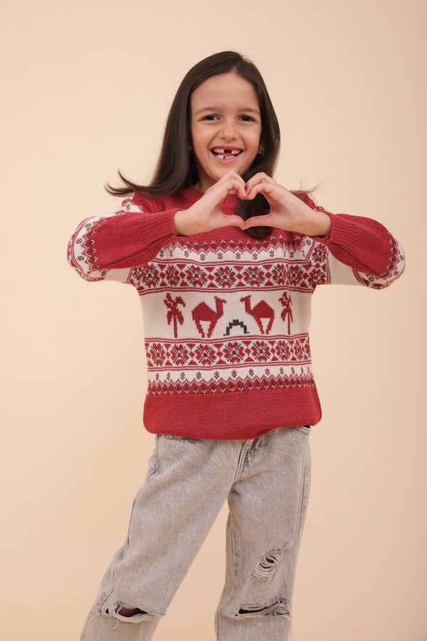 Enfant en pull de Noël LYOUM rouge qui fait coeur avec les mains.