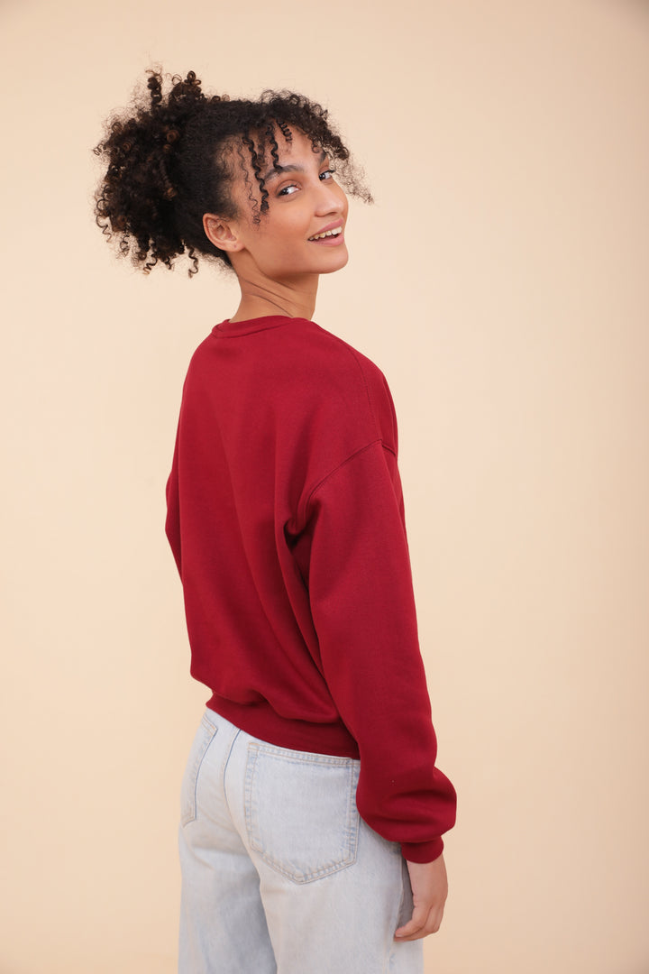 Vue de dos du sweat LYOUM rouge porté par une femme aux cheveux bouclés.