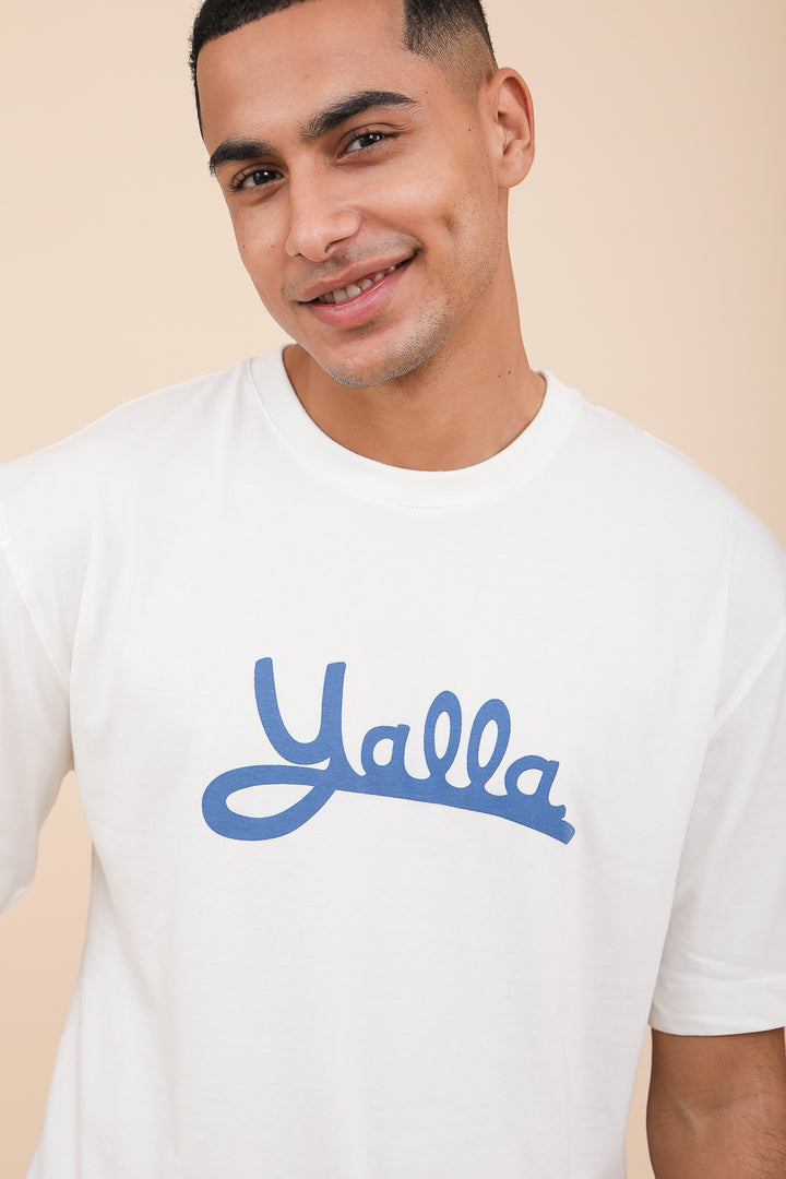 Homme en tshirt blanc et Yalla écrit en bleu dessus.