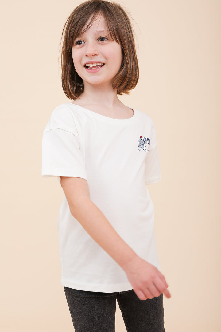 Petite fille souriante portant un t-shirt blanc LYOUM en coton.