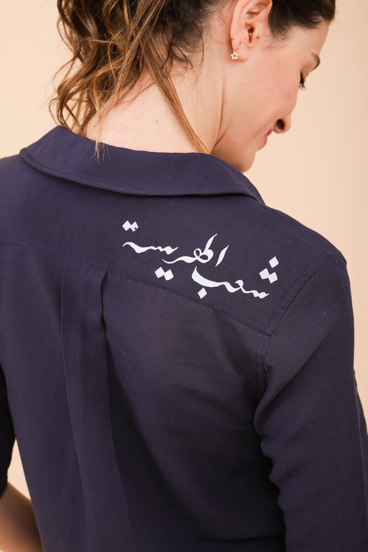 Elégante calligraphie arabe 'Harissa People' derrière l'épaule.
