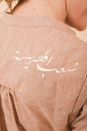 Calligraphie arabe 'Harissa People' brodée sur l'épaule en fil écru.