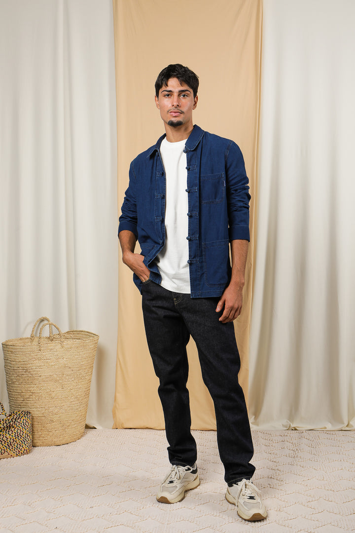 Homme en veste dengri en jeans et tshirt blanc, la main dans la poche.