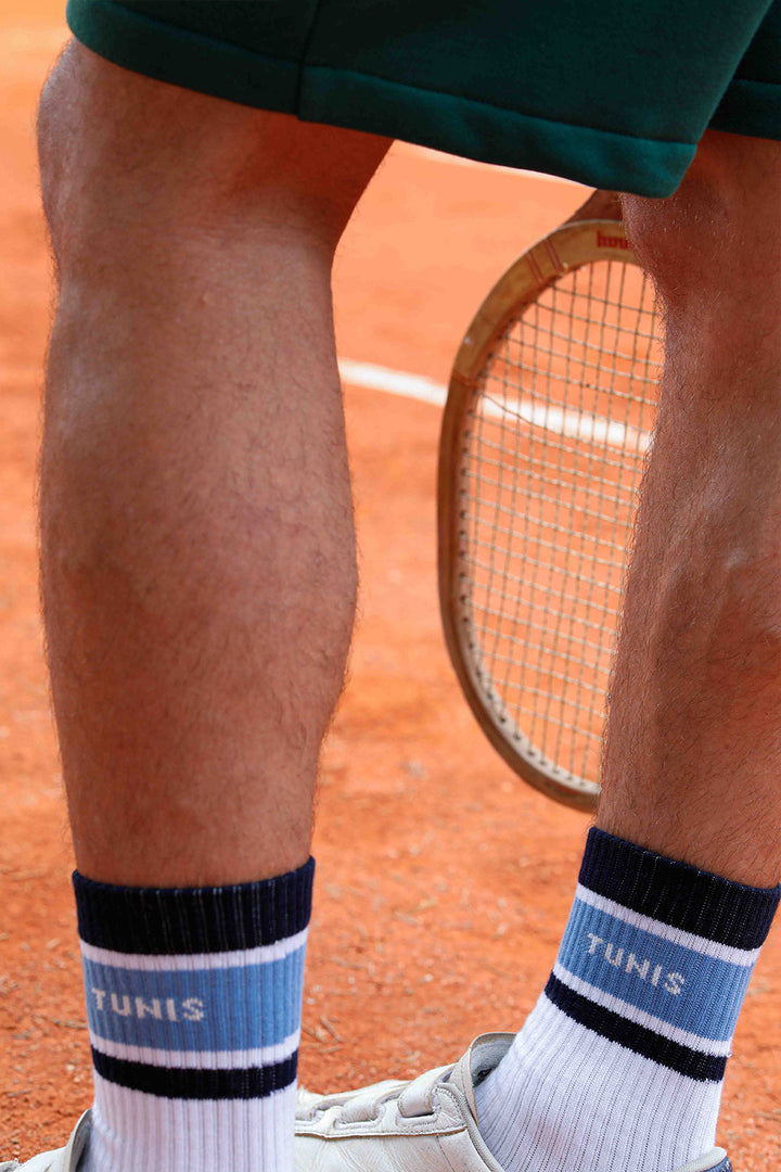 Chaussettes blanches mi- hautes avec rayures navy et bleu gris, aux accents rétro vintage. Signature LYOUM 'Tennis' tricoté sur un côté et 'Tunis' de l'autre.