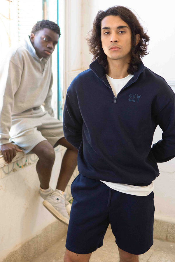 Deux hommes en ensemble LYOUM sweat et short en molleton brodés.