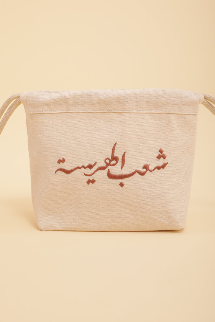 Découvrez la pochette Harissa by LYOUM avec notre belle calligraphie 'Le Peuple de la Harissa' brodée sur un côté, en fil couleur bronze.