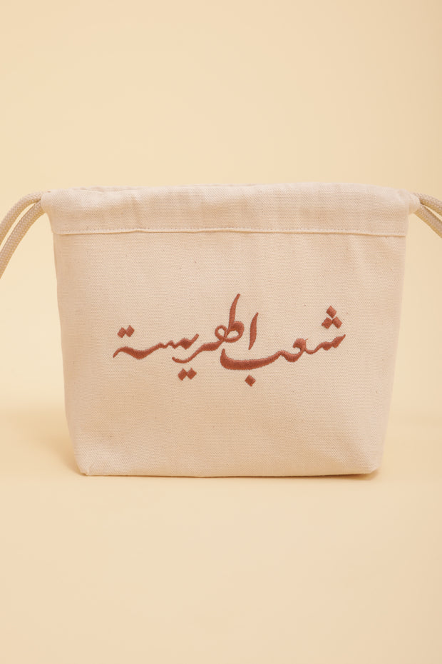 Découvrez la pochette Harissa by LYOUM avec notre belle calligraphie 'Le Peuple de la Harissa' brodée sur un côté, en fil couleur bronze.