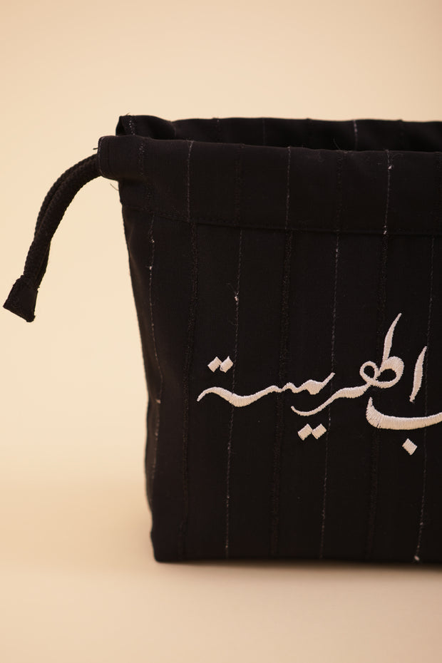 Pochette à cordant avec broderie 'Peuple de la Harissa' en arabe sur un côté.