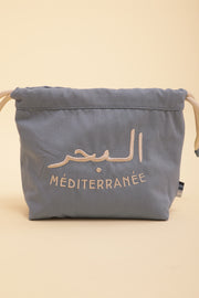 Découvrez la nouvelle pochette à coulisse by LYOUM avec notre message iconique 'La Mer Méditerranée' en arabe/français brodé sur un côté, en fil beige clair.