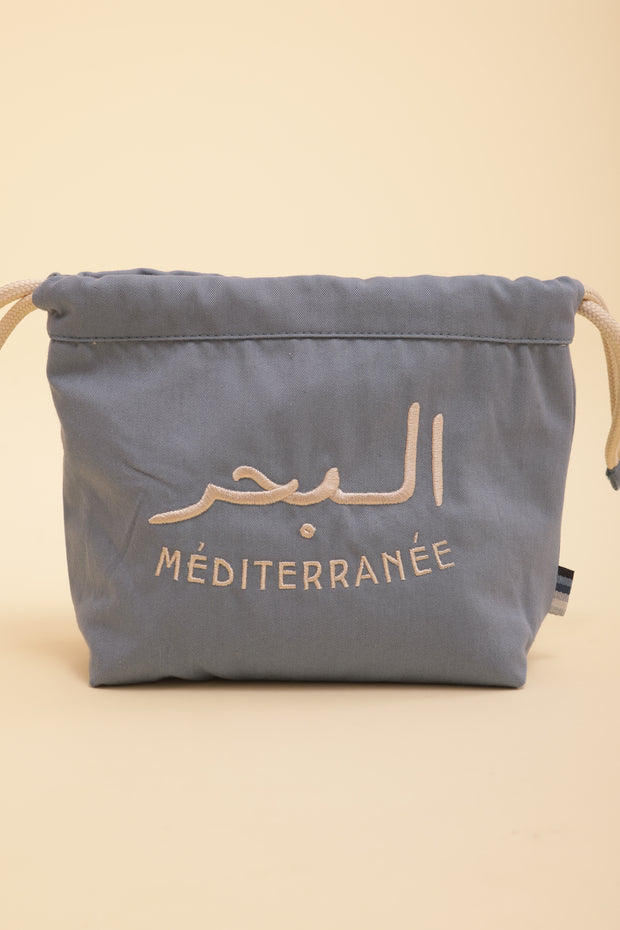 Découvrez la nouvelle pochette à coulisse by LYOUM avec notre message iconique 'La Mer Méditerranée' en arabe/français brodé sur un côté, en fil beige clair.
