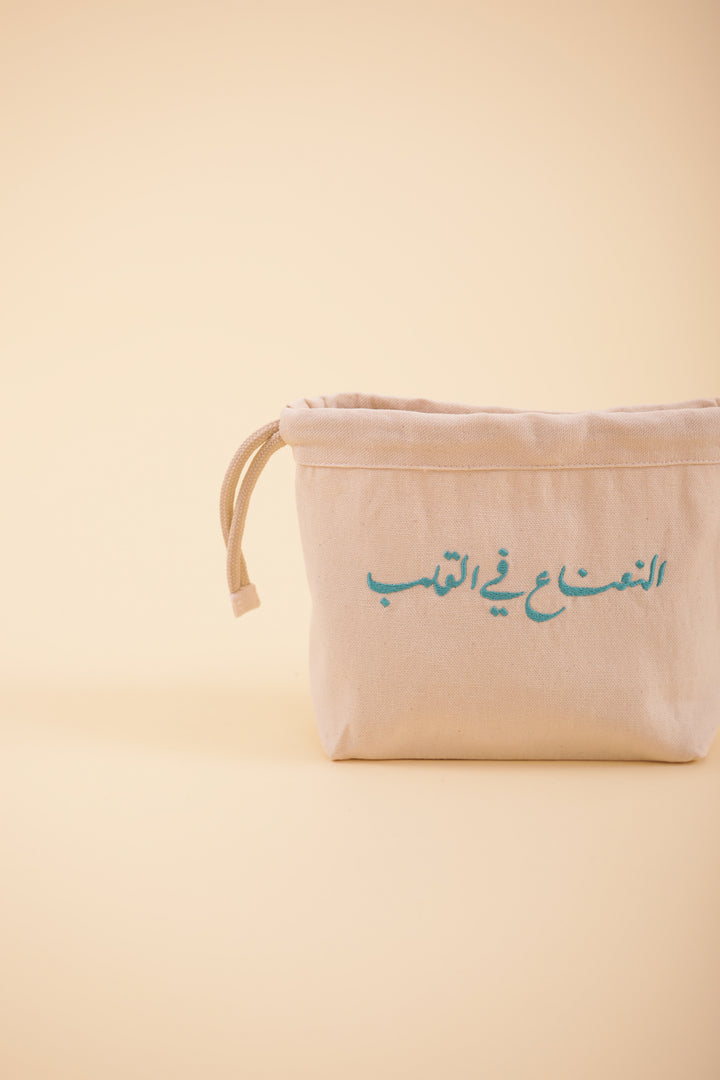 Pochette à cordant avec broderie notre message exclusif 'La Menthe dans le Coeur' en calligraphie arabe, brodé sur un côté, en fil vert-d'eau. La petite trousse idéale et pratique à emporter partout.