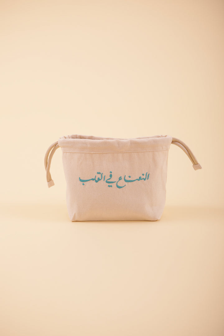 Pochette à cordant avec broderie notre message exclusif 'La Menthe dans le Coeur' en calligraphie arabe, brodé sur un côté, en fil vert-d'eau. La petite trousse idéale et pratique à emporter partout.