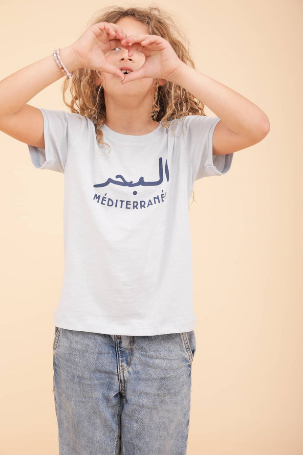 Nouveau t-shirt pour enfant. Coupe droite et col rond, le tout dans une matière douce et fluide en coton, couleur bleu méditerranée