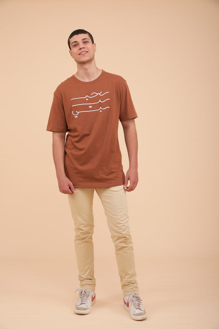 Silhouette LYOUM homme pantalon crème et tshirt terracotta calligraphie.