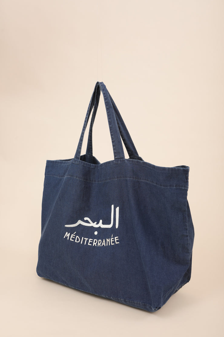 Grand sac de plage en toile de coton bleu moyen avec broderie 'La Mer Méditerranée' en arabe et français, couleur crème.