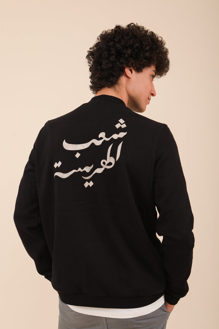 Nouvelle Veste Bomber pour homme by LYOUM. Veste iconique en molleton ultra-agréable, avec notre broderie en calligraphie iconique au dos (‘le Peuple de la Harissa' en arabe), coupe droite ajustée. Petit détail ‘LYOUM’ brodé au coeur, ton sur ton.