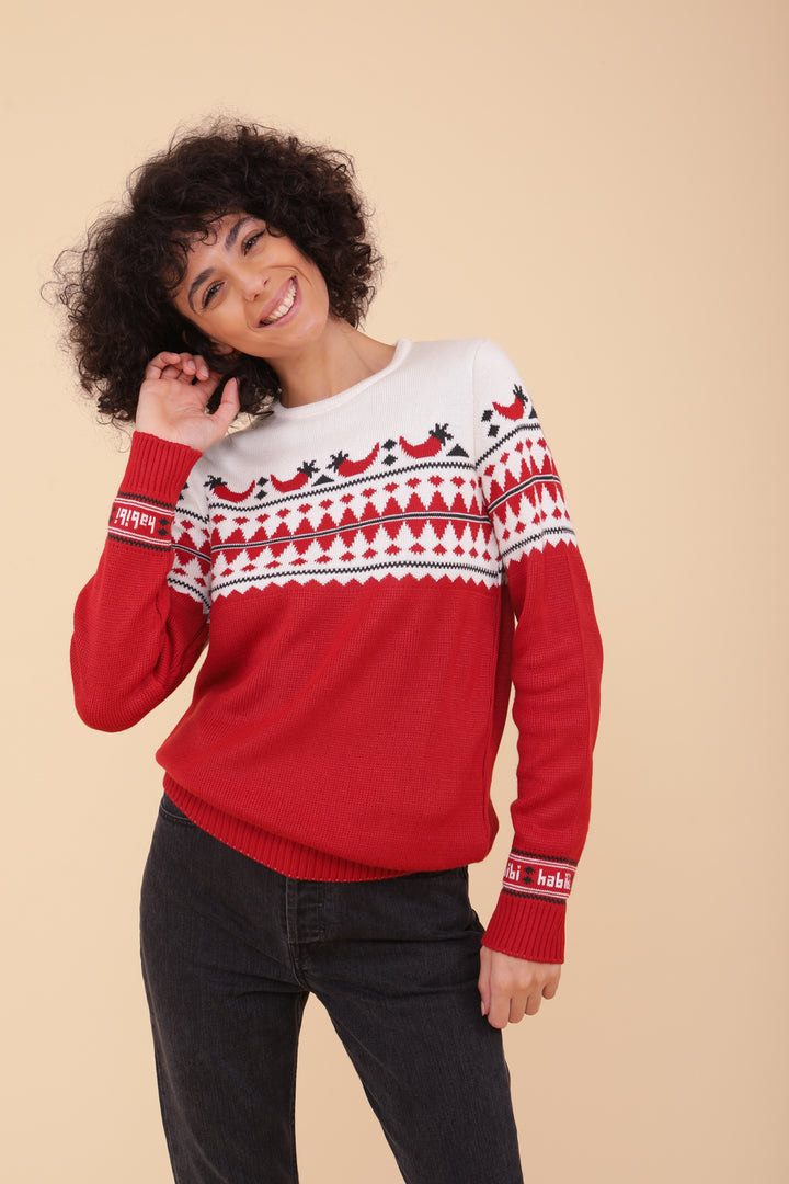 Femme en jeans noir et pull de Noël LYOUM rouge motif piments et Habibi.