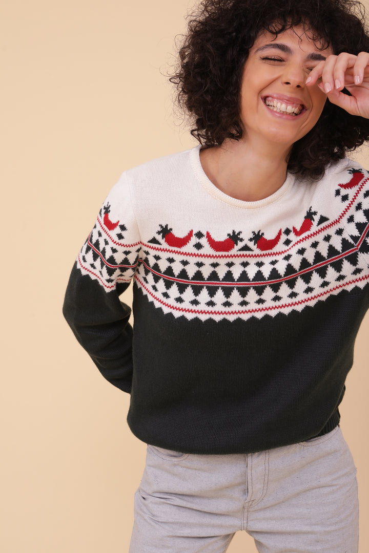 Femme aux cheveux bouclés en pull de Noël à motif piments.