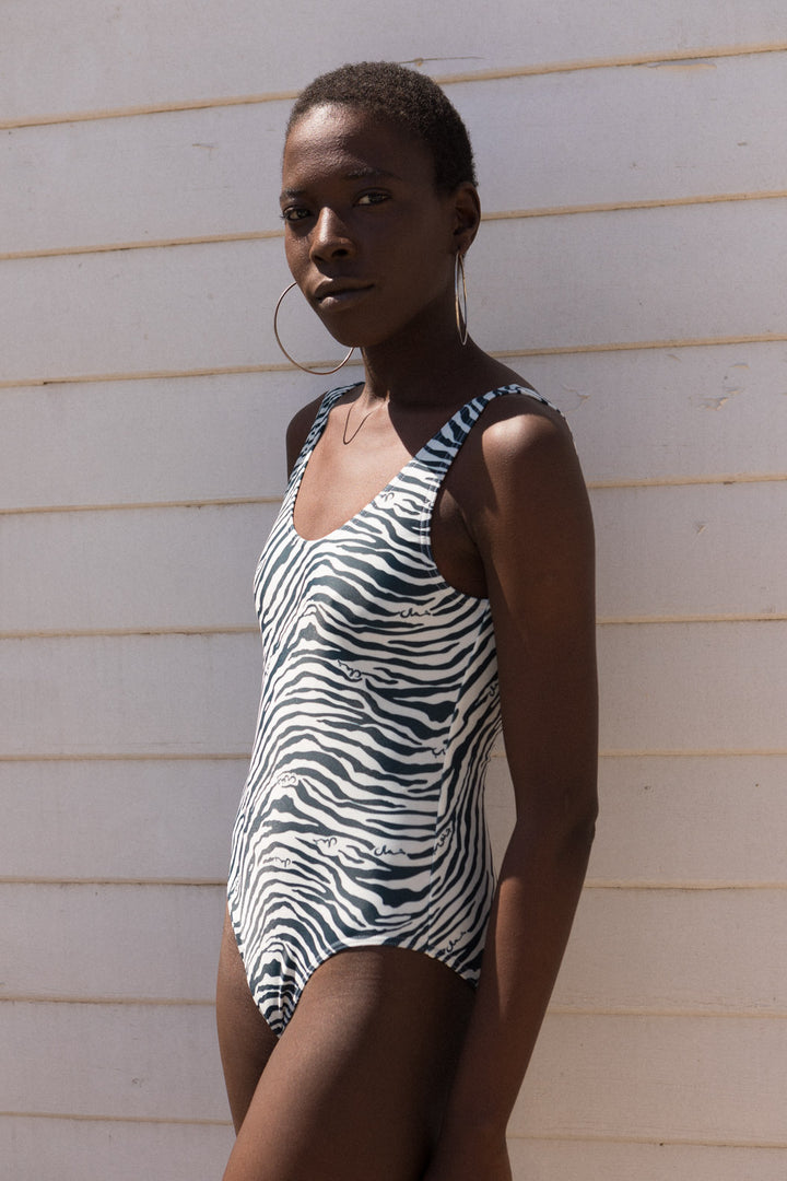 Maillot de bain LYOUM pour femme chic et élégant. Imprimé zébré blanc et bleu navy avec trois petits mots 'Nord' 'Sud' et 'Beauté' en calligraphie arabe dissimulés dans les zébrures.  Photo de face..